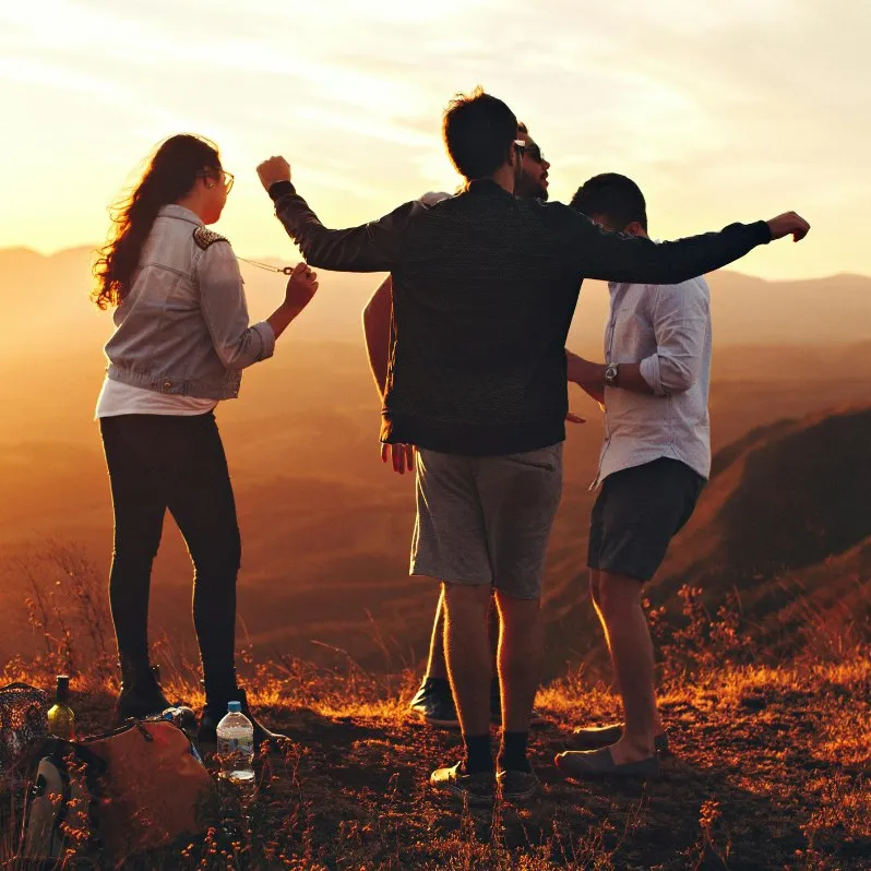 Groupe d'amis de dos face à un coucher de soleil