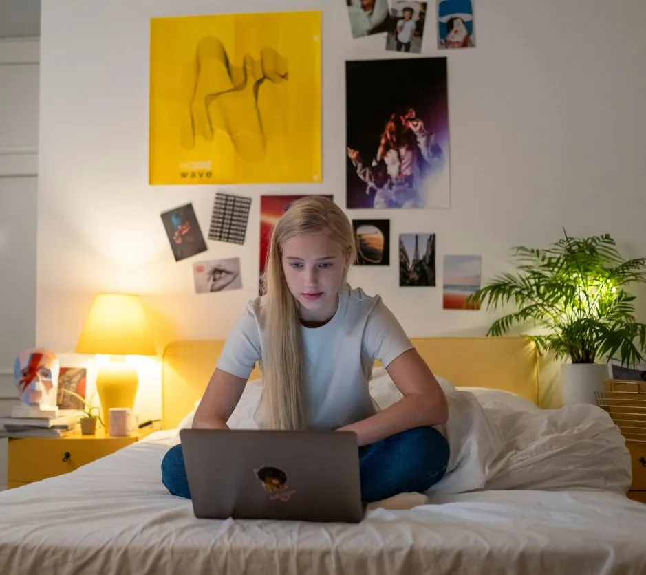 Étudiante travaillant sur son ordinateur dans sa chambre
